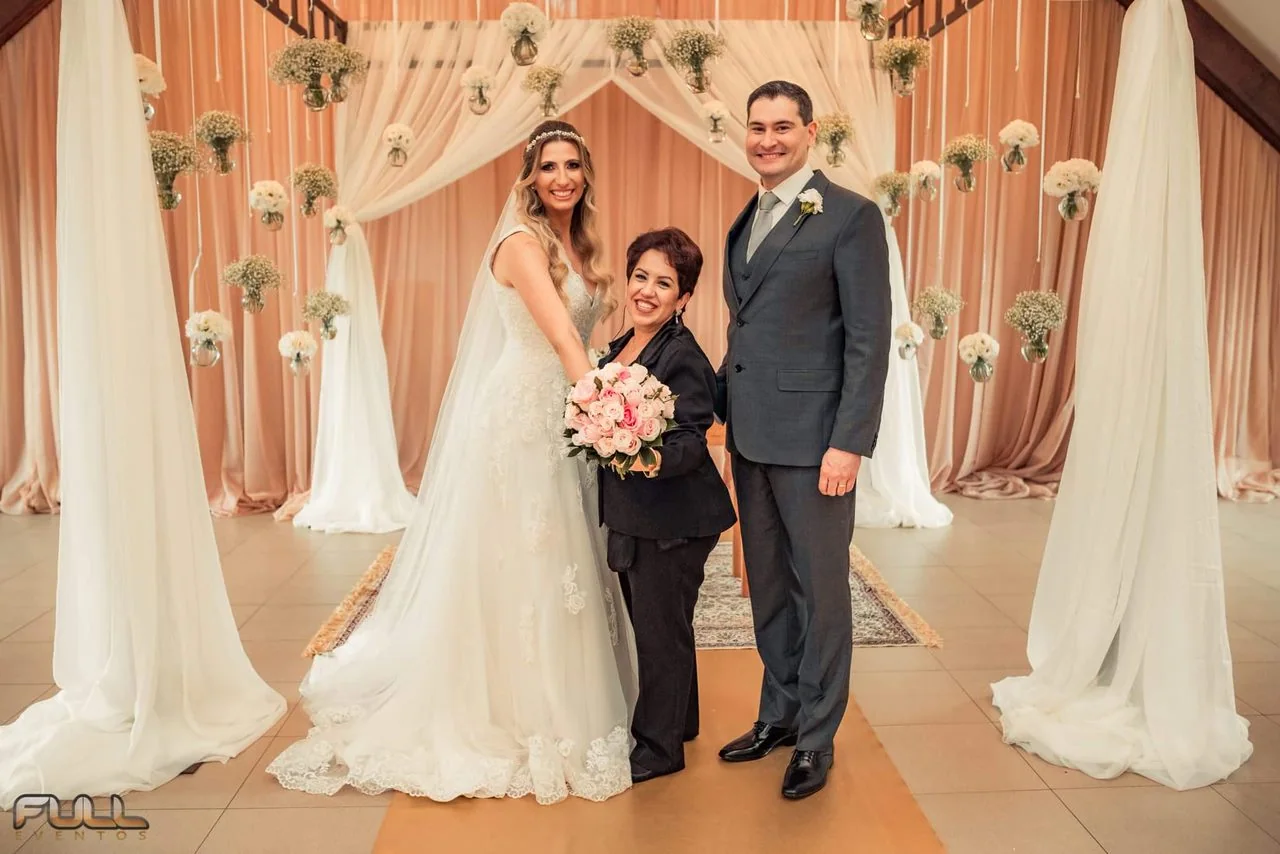 Juliana Porto com os noivos diante da decoração floral.